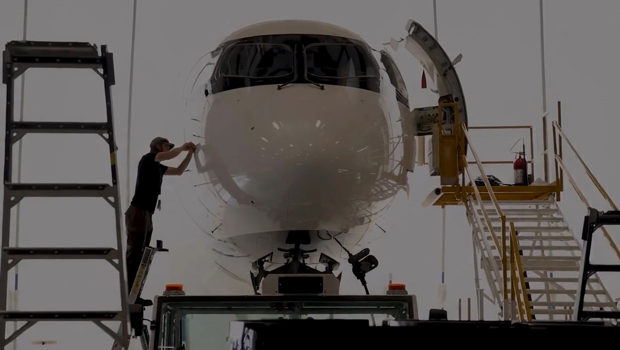 Technicien Avianor travaillant sur le nez d'un A220 en hangar